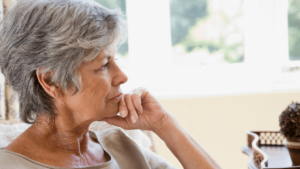 A senior woman sitting, lost in thought.